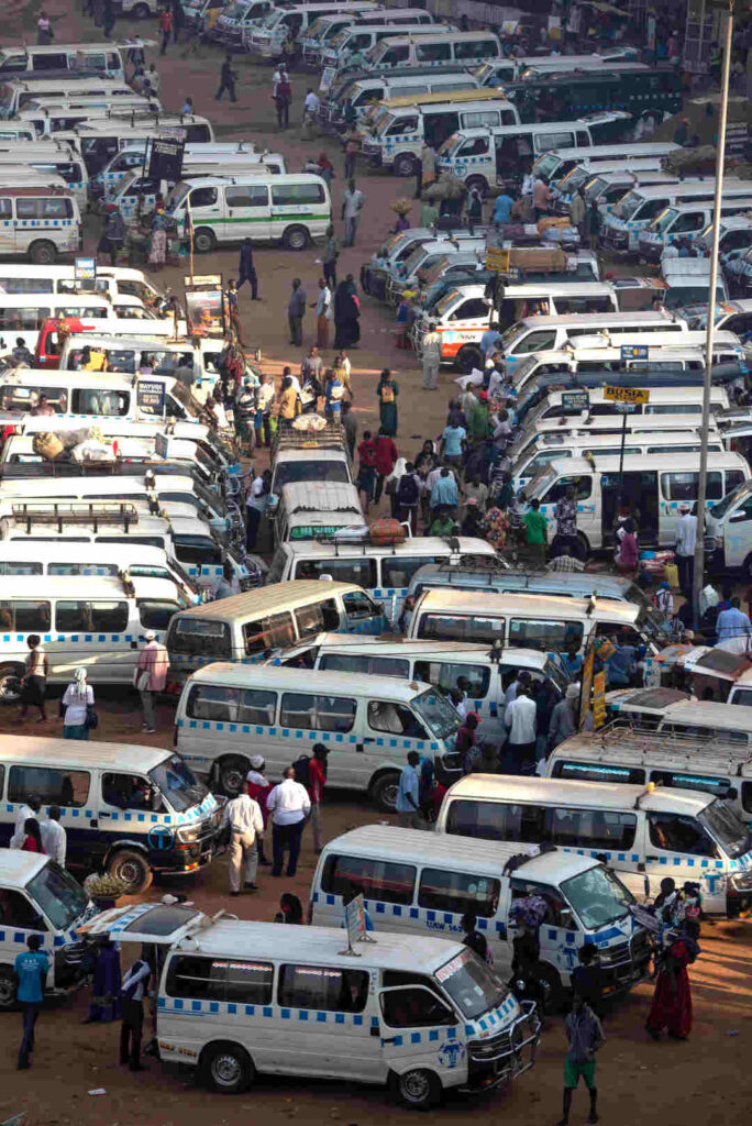 Rows and rows of white minibus style taxis line up in Kampala, Uganda at the Old Taxi Park